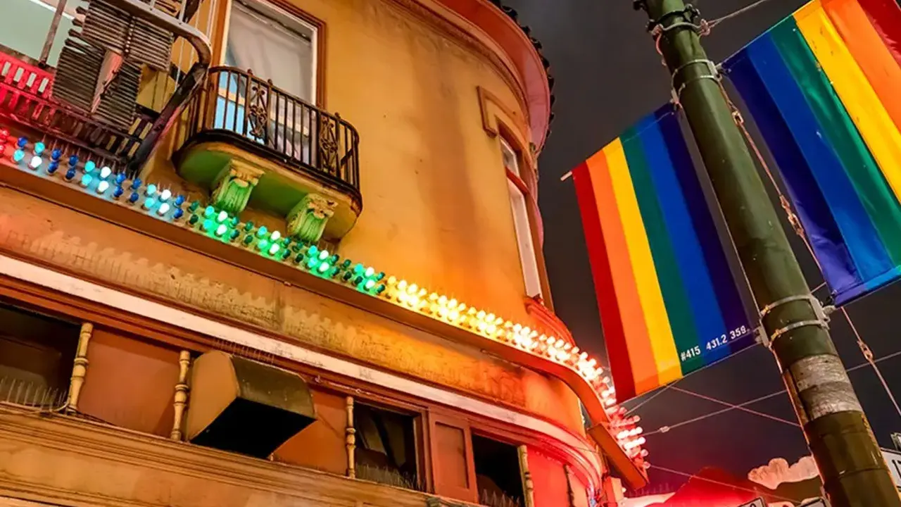 Rainbow flags fly proudly in the gayest city in America, illuminating a building with colorful lights.