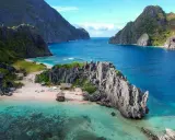 A secluded beach in the Philippines, with turquoise waters, limestone cliffs, and small huts. A perfect gay getaway in paradise.