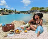 Two women enjoy a picnic on a beach in Curacao, a gay-friendly paradise.