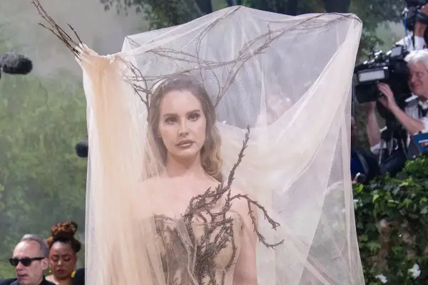 Lana Del Rey at the Met Gala, adorned in a ethereal gown with branches and sheer veil, looking like a forest nymph.